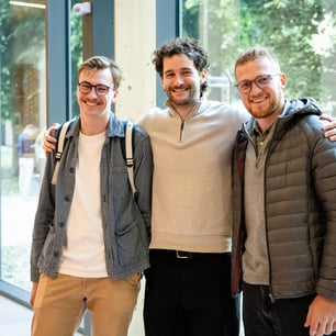 trois amis souriant ensemble debouts face à la caméra