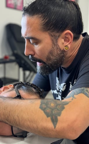 Tattoo Artist Ruben Enriquez while doing a tattoo on a client