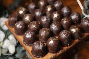 Deliciosos chocolates trufados apresentados em uma bela bandeja de madeira, ideais para festas e oca