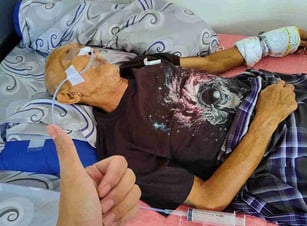 a man in a hospital bed with an ngt tube attached