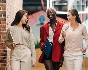 three women in business attire walking down a hallway