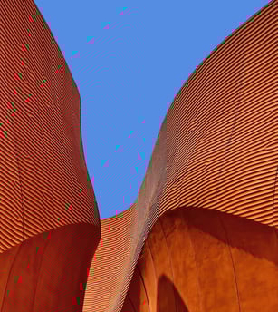 Bâtiment orangé et courbe sur un ciel bleu