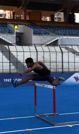 a man is jumping over a hurdle in a stadium