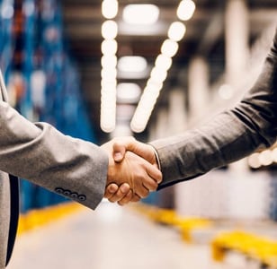 Handshake of two professionals in warehouse — symbolising trusted logistics partnerships in Qld.