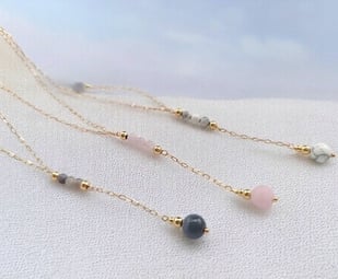 Ensemble de 3 colliers en plaqué or et pierre naturelles, sur du sable 