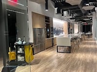 A large open-style kitchen at an office building with a janitorial cart in front of it.