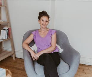 a woman sitting in a chair with a bookcase