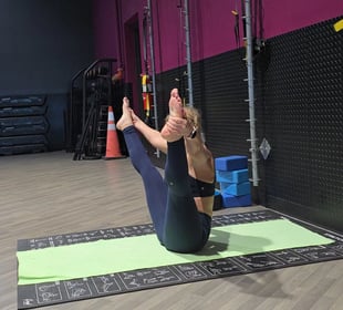 Eva guiding a private yoga session indoors in boat pose (Navasana)