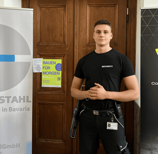 Eine Sicherheitskraft in "SECURITY"- Shirt vor einer Tür