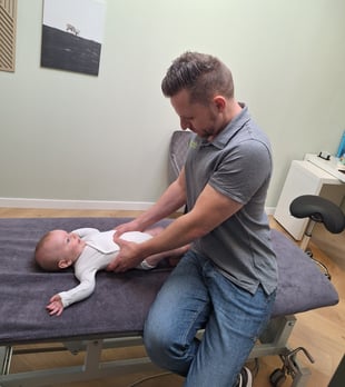 een man geeft een manuele behandeling aan een baby in zijn buik