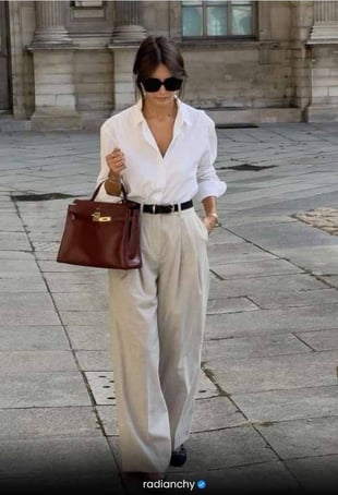 a woman in a white shirt and pants with a brown bag