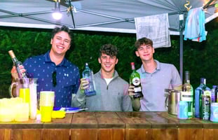 three men standing at a bar with drinks