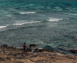 a person standing on a rock in the ocean