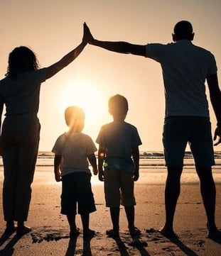 uma família de três pessoas em pé na praia