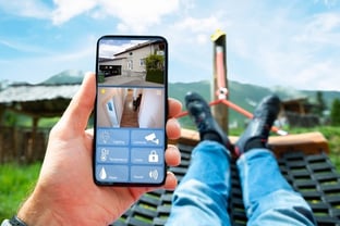 man laying in hammock looking at remote video of his home