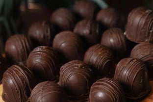 Uma deliciosa seleção de bombons de chocolate dispostos em uma superfície de madeira, destacando a f