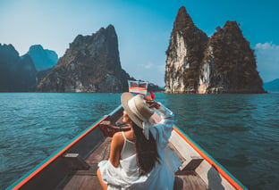 girl solo travelling on a boat overlooking Thailand landscape