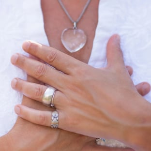 lady's hands clasped over her chest in a peaceful way she wears a white blouse and jewellry