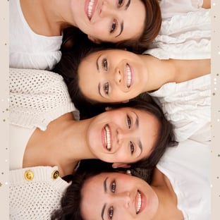 4 ladies lying head to head in a line all wearing white and smiling