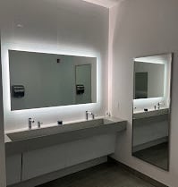 A mirror, sink, and faucets inside a modern bathroom.