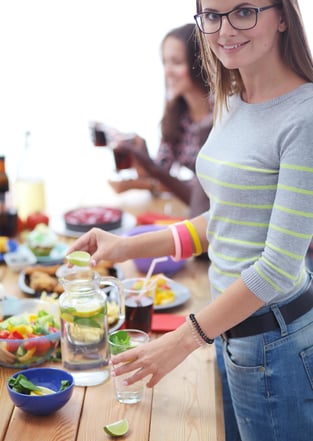 Vrouw die voor een tafel staat met een gezonde salade, symbool voor gezonde voeding of lifestyle.