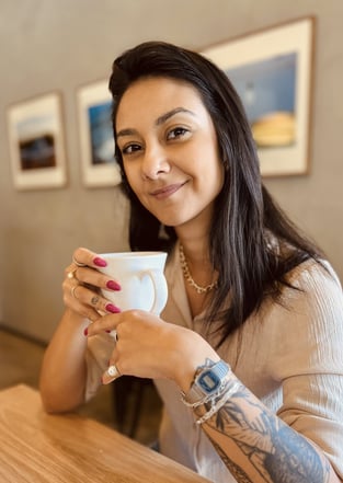 a woman with tattoos on her arm and a cup of coffee