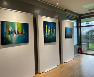 une salle d'exposition avec trois tableaux on the walls