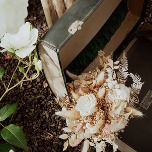 photographie d'un bouquet de mariage fait en  fleurs séchées mis en avant dans une valise