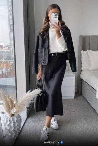a woman in a black leather jacket and white sneakers