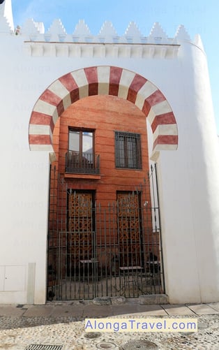 Horseshoe arched doorway of a building with white & pink bricks in Mudejar style 