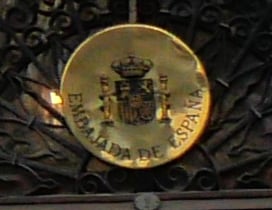 A golden emblem of Embajada de Espana with Spanish coats-of-armsh brown 