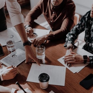 a group of people sitting around a table with papers and papers