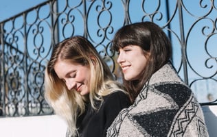 two women sitting on a bench in a park