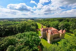 a castle like building with a large tower in the middle of a lush green field