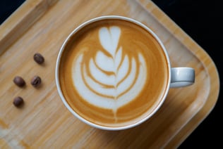 a cup of coffee with a leaf design on the side