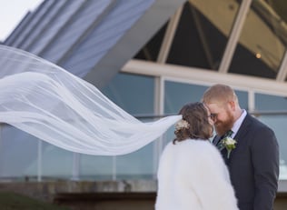 Bride and groom standing face to face, her veil flowing behind. Canberra wedding photographer.