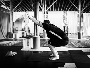 A man executes the chair pose during yoga class.