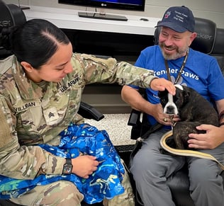 A female Soldier interacts with Tender Paws Therapy Dog Piper and her Handler, FDavid.