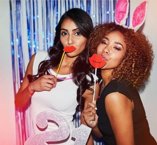 two women posing for a photo booth at a party