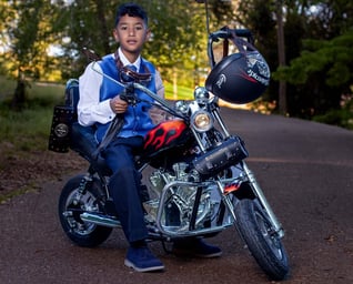 niño comunion montado en su moto  roja y  negra        