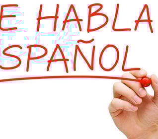 a hand writing spanish words on a white board