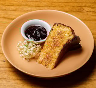 a plate of a slice of cheesecake and a bowl of jam