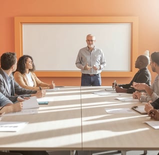 a man in a suit and tie is standing in front of a boardroom table