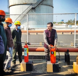 a man gives training of fire safety to a group of people  who wear suits and helmet 