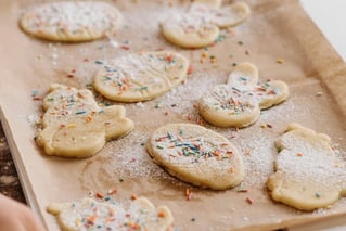 a person holding a cookie cookie on a baking sheet
