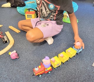 autistic boy playing with a train set up on the floor