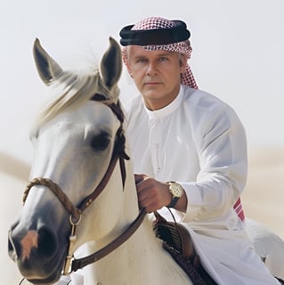 Peter Pickering dressed in Arab garb riding a white Arab stallion