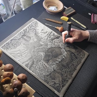 a person is working on a linocut using a fine cutting tool