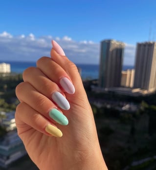 a person's hand with pastel colored manicure with each finger a different color