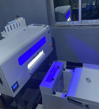 a DTF machine turned on, with bright blue lights shinning from it.